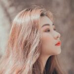 Close-up portrait of a young woman with long hair posing outdoors with a serene expression.